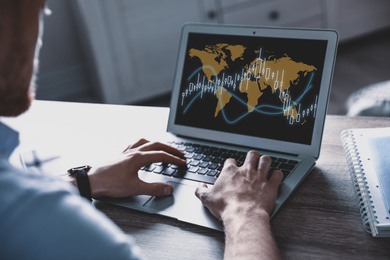 Image of Broker using laptop at table indoors, closeup. Forex trading