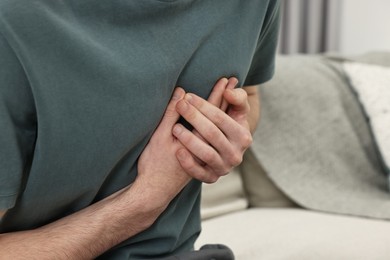 Photo of Man suffering from heart hurt on sofa at home, closeup