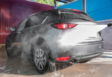 Cleaning automobile with high pressure water jet at car wash