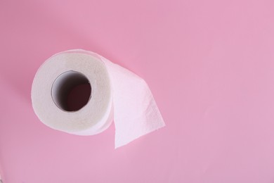 Photo of Soft toilet paper roll on pink background, top view. Space for text