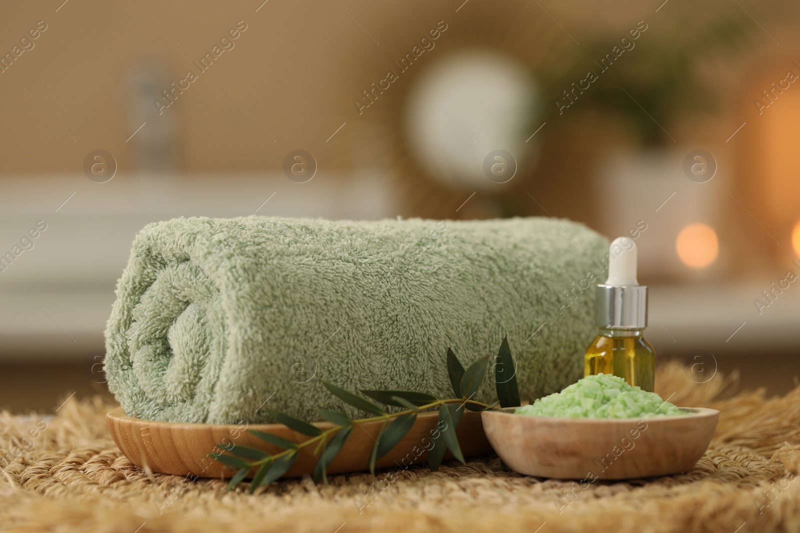 Photo of Spa composition. Rolled towel, cosmetic product, sea salt and twig on table indoors