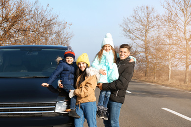 Photo of Happy family with little children near modern car on road