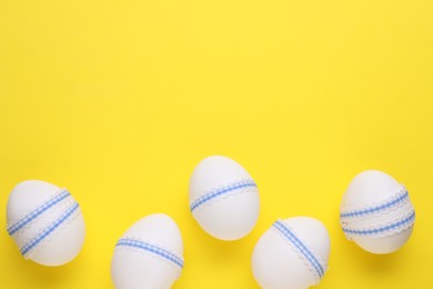 Photo of Festively decorated Easter eggs on yellow background, flat lay. Space for text