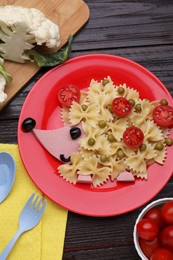 Photo of Creative serving for kids. Plate with cute hedgehog made of delicious pasta, sausages and tomatoes on black wooden table, flat lay