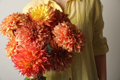 Woman with bouquet of beautiful dahlia flowers on grey background, closeup