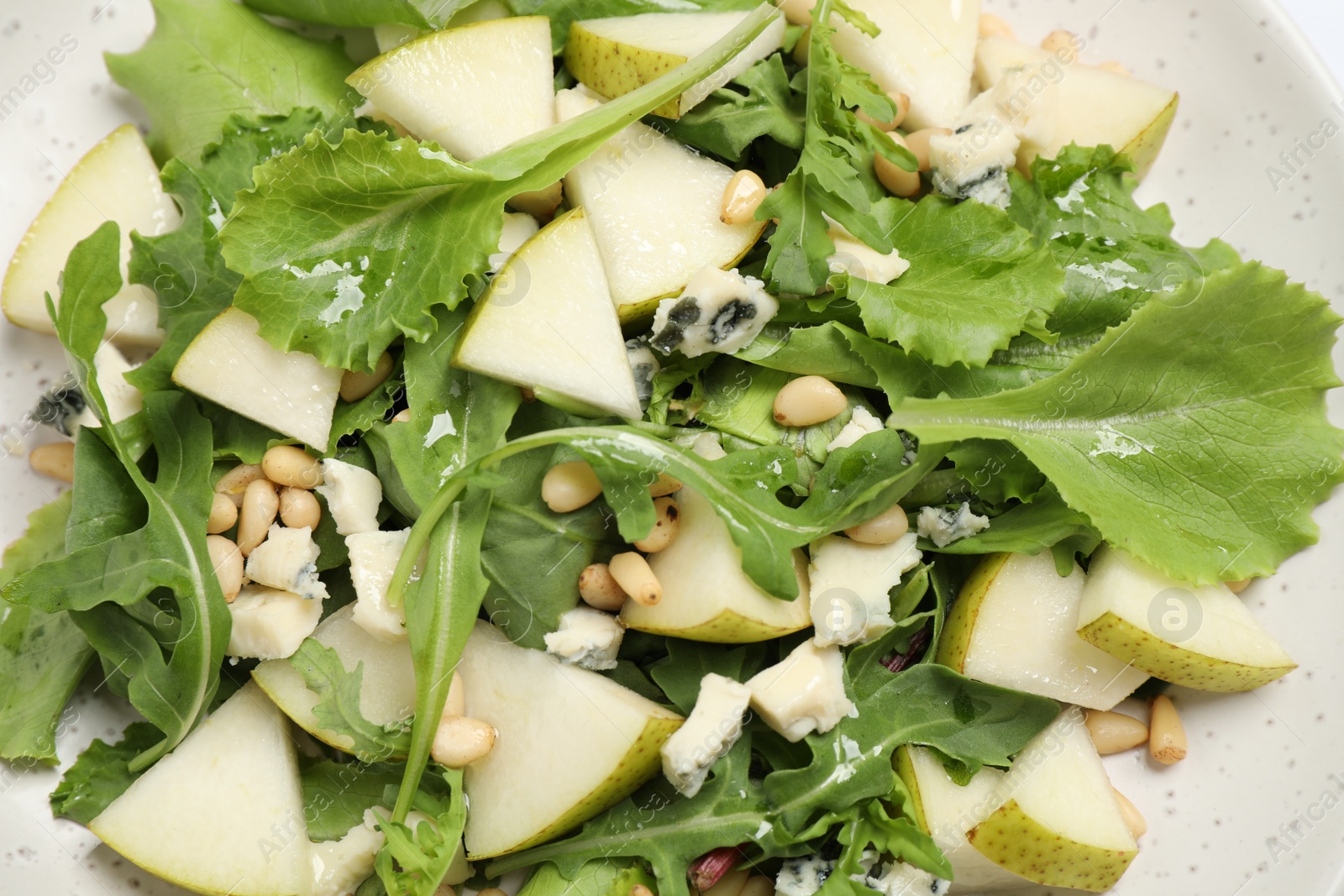 Photo of Tasty salad with pear slices, lettuce and pine nuts as background, closeup