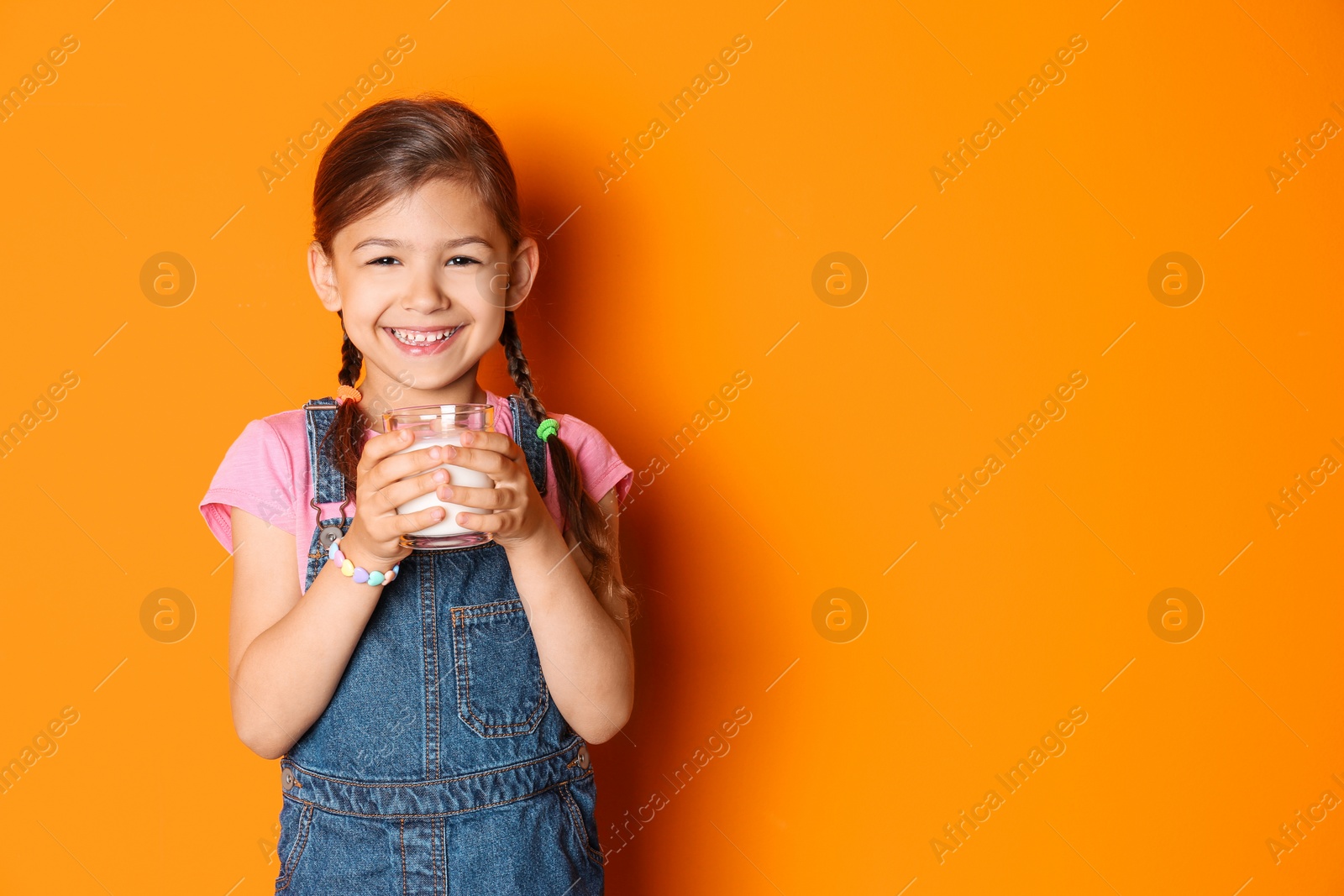 Photo of Cute little girl with glass of milk on color background