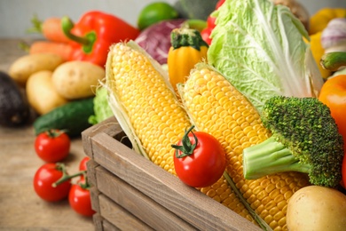 Photo of Fresh vegetables and wooden crate on table, closeup