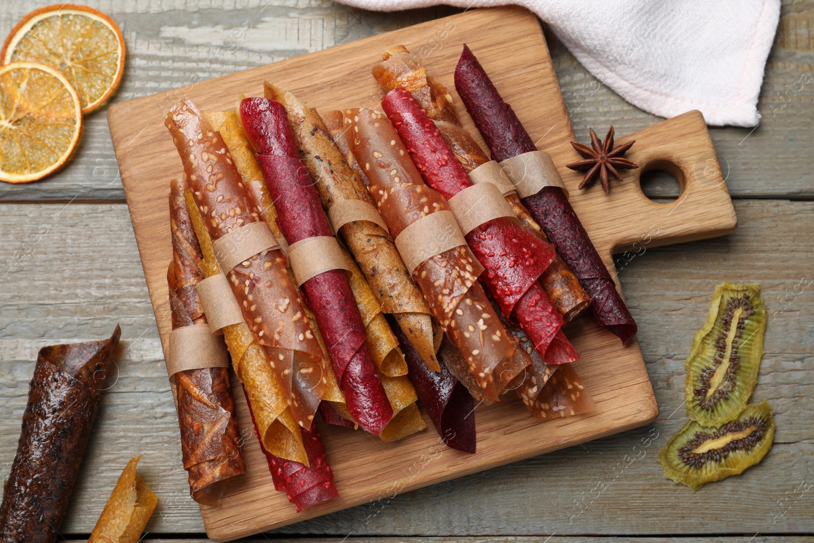 Photo of Delicious fruit leather rolls on wooden table, flat lay