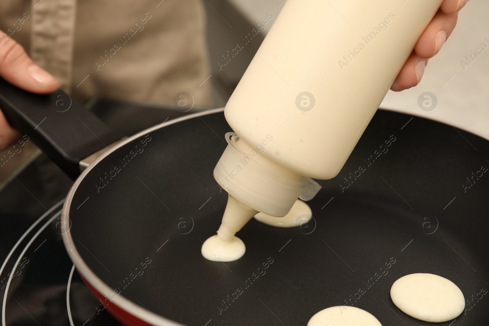 Photo of Woman cooking cereal pancake on frying pan, closeup