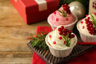 Photo of Delicious cupcakes and Christmas decorations on wooden table, space for text