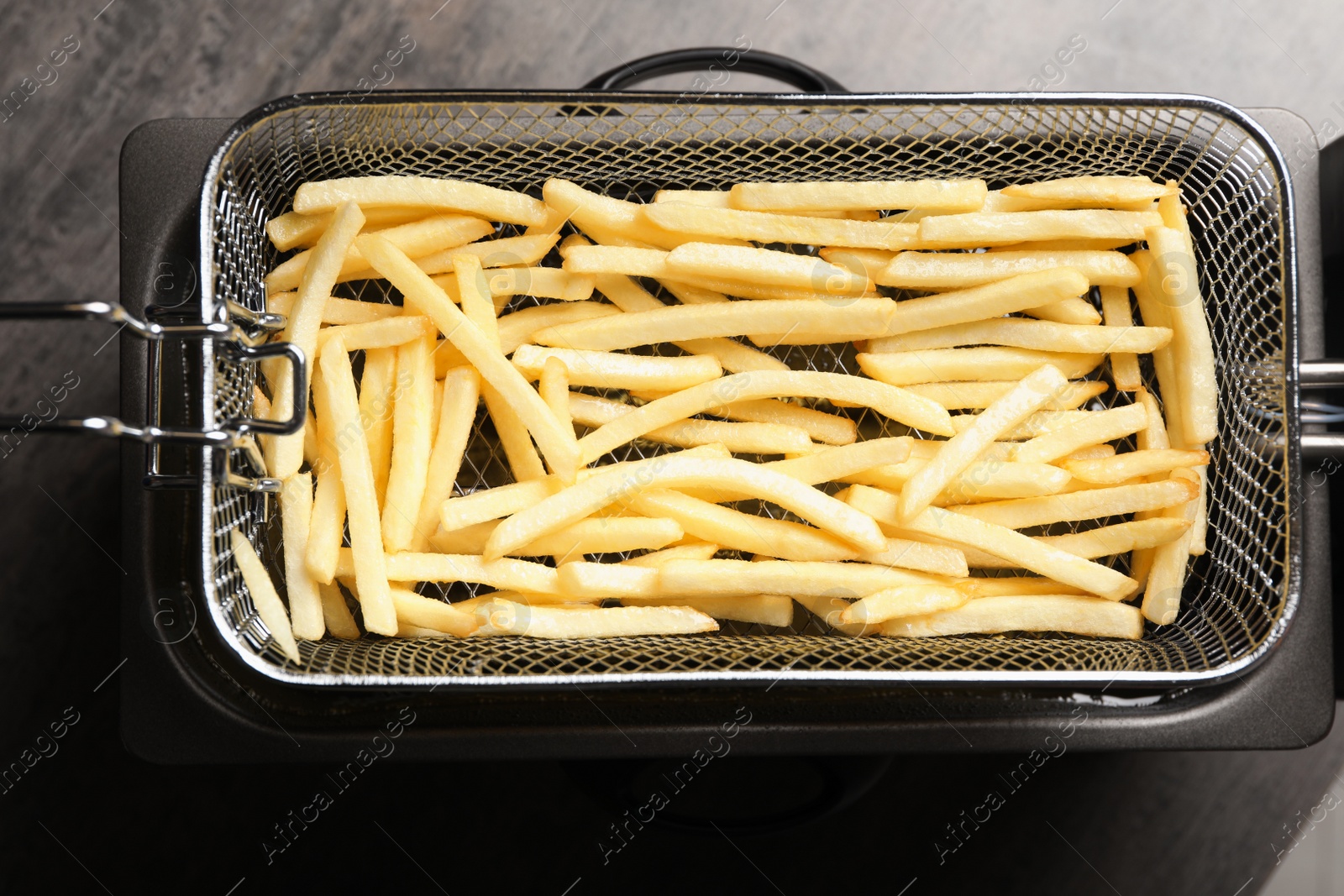 Photo of Cooking delicious french fries in hot oil, top view