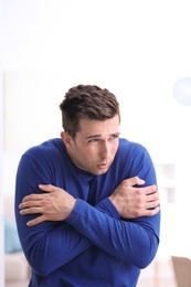 Photo of Sad young man suffering from cold on blurred background