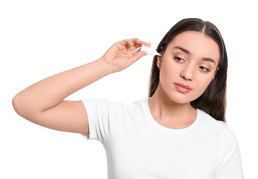 Young woman using ear drops on white background