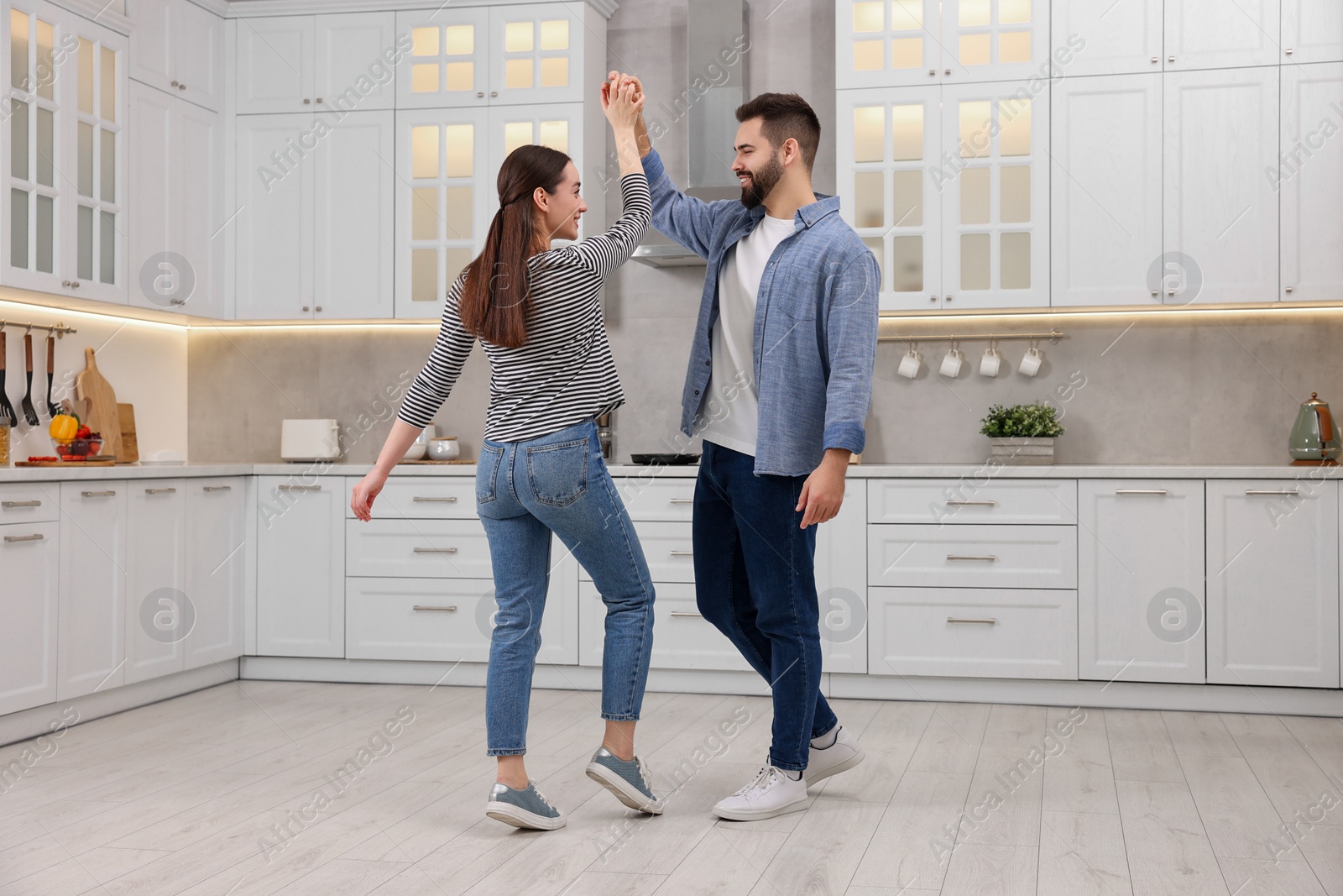 Photo of Happy lovely couple dancing together in kitchen