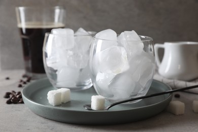 Making iced coffee. Ice cubes in glasses, ingredients and spoon on gray table, closeup