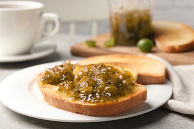Photo of Slice of toasted bread with gooseberry jam on grey table, closeup