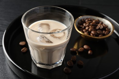 Coffee cream liqueur in glass and beans on table, closeup