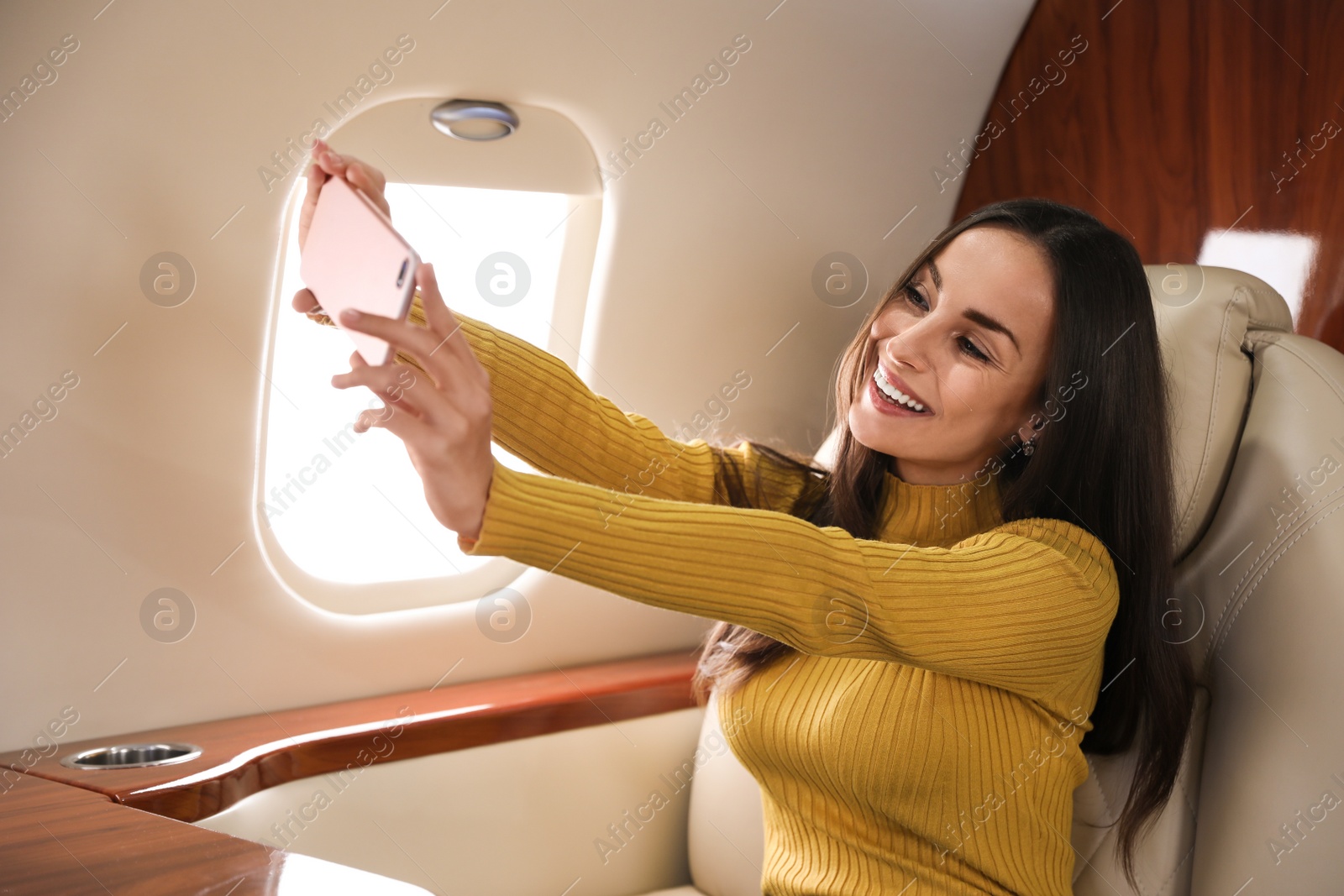 Photo of Young woman taking selfie on plane. Comfortable flight