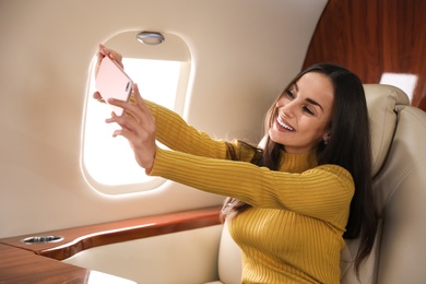 Young woman taking selfie on plane. Comfortable flight