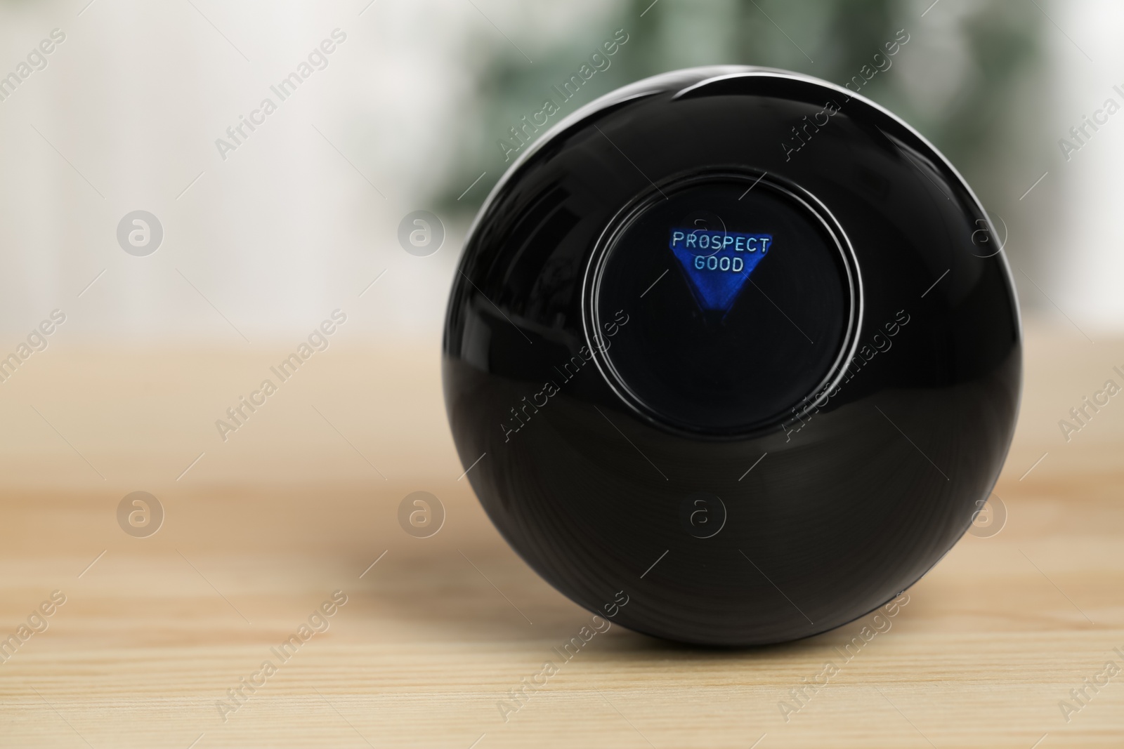 Photo of Magic eight ball with prediction Prospect Good on wooden table, closeup. Space for text