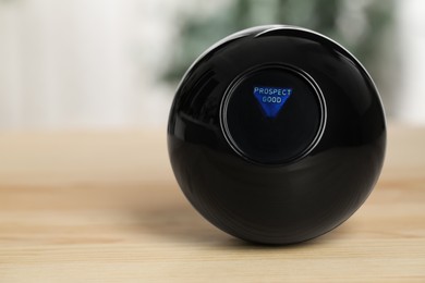 Photo of Magic eight ball with prediction Prospect Good on wooden table, closeup. Space for text