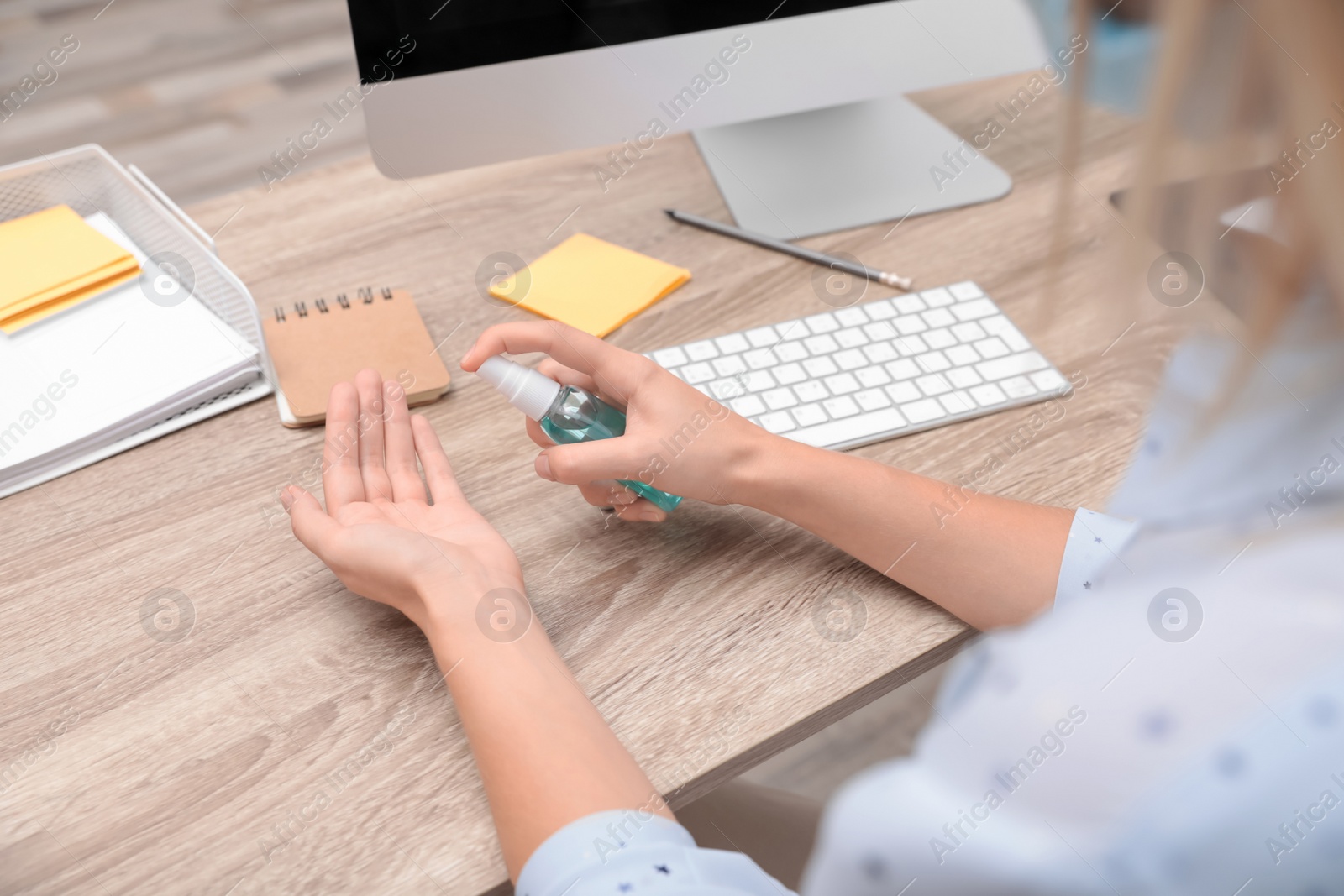 Photo of Office employee applying hand sanitizer at workplace, closeup