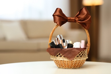 Photo of Wicker basket full of gifts on white table in living room. Space for text