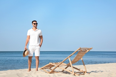 Photo of Young man near deck chair on beach near sea