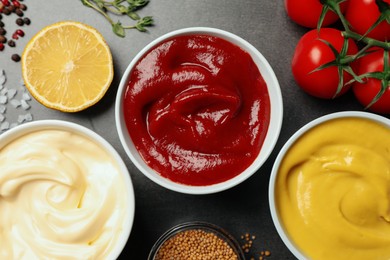 Photo of Flat lay composition with ketchup, mustard, mayonnaise and ingredients on grey table