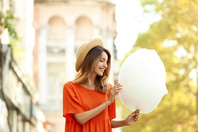 Photo of Happy young woman with cotton candy outdoors