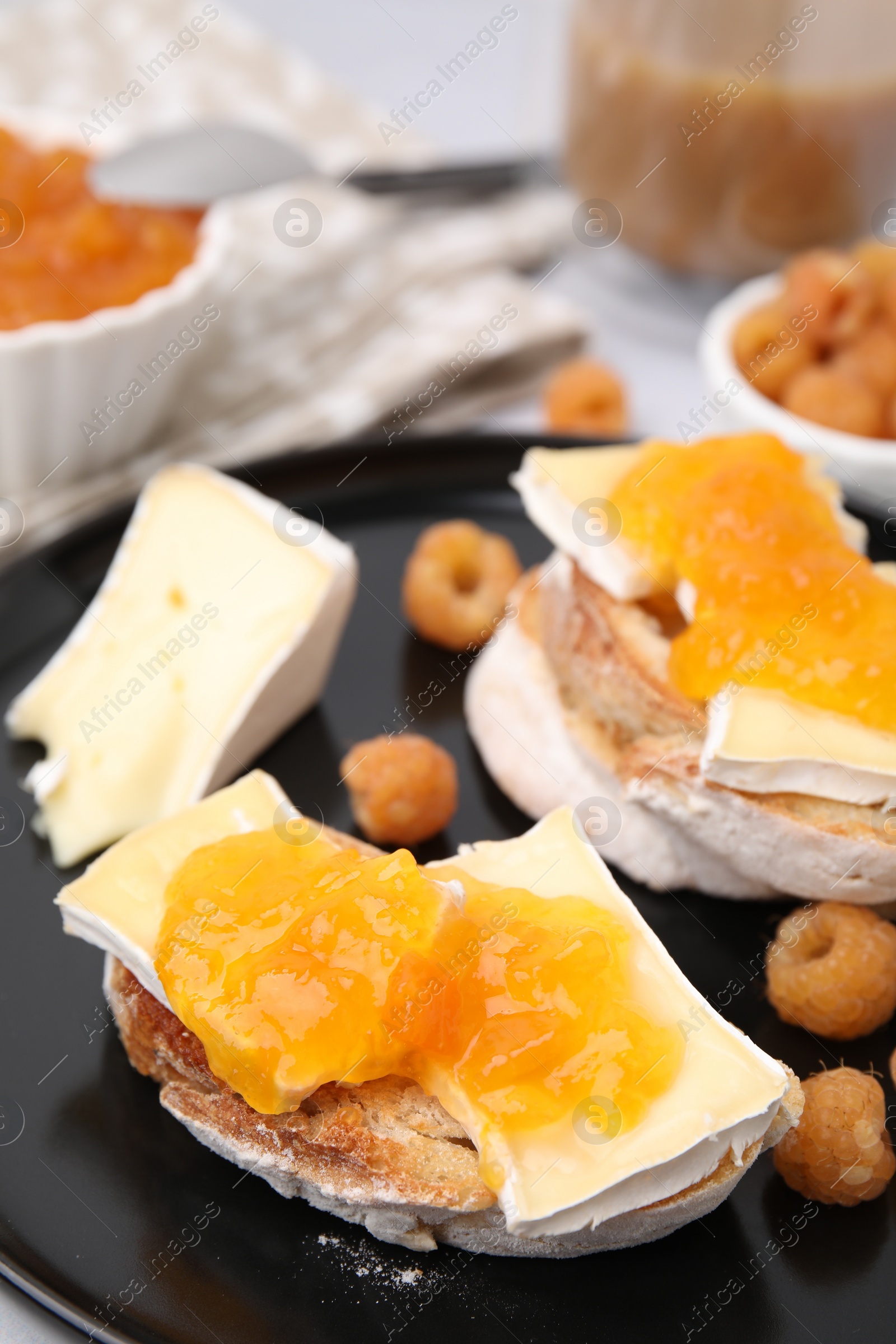 Photo of Tasty sandwiches with brie cheese, fresh raspberry and apricot jam on table, closeup