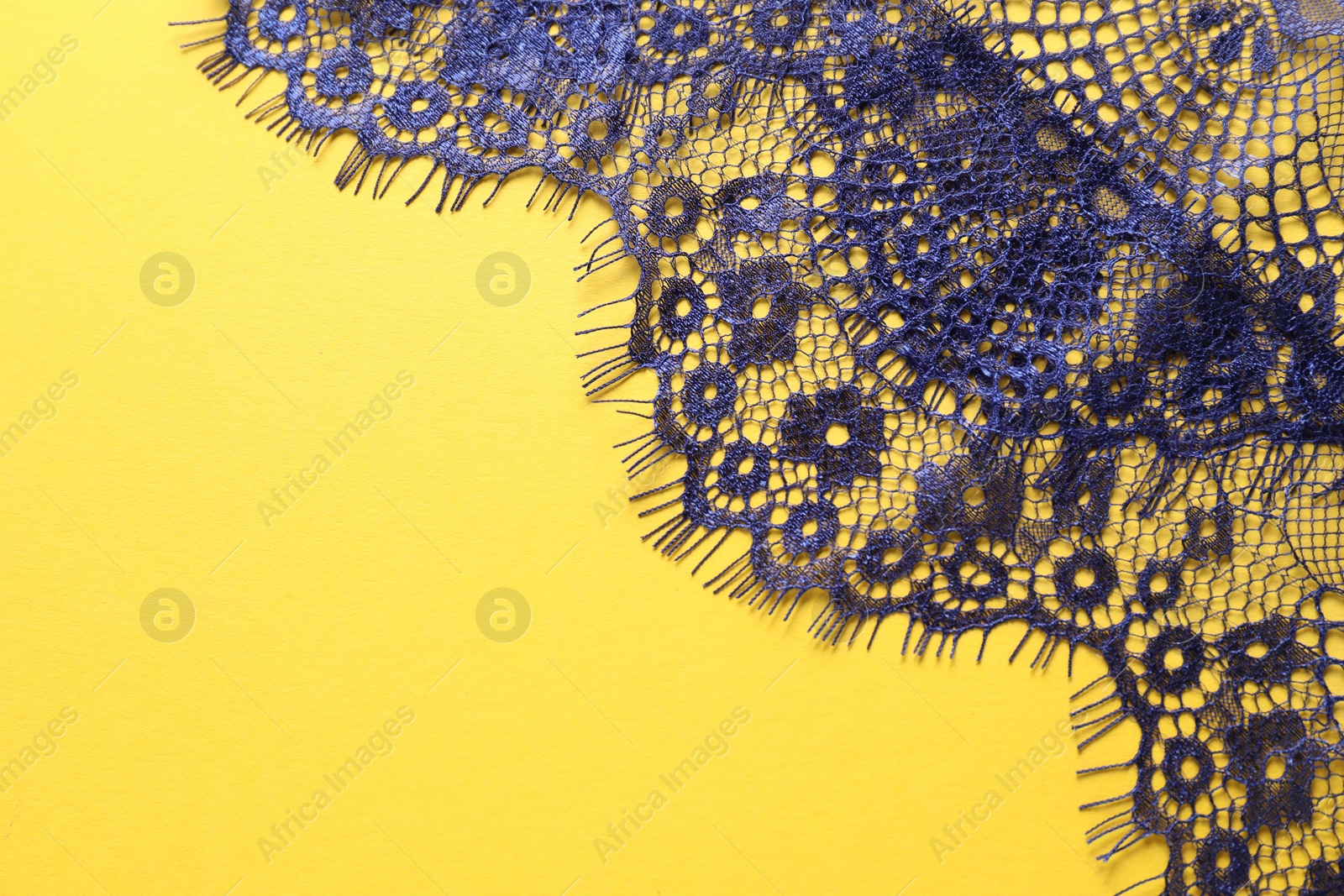 Photo of Blue lace on yellow background, top view. Space for text