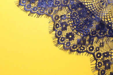 Blue lace on yellow background, top view. Space for text