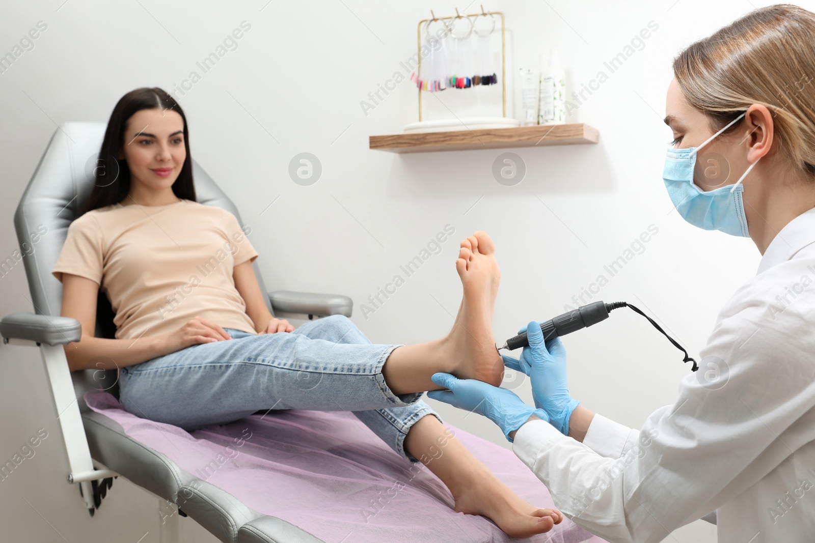 Photo of Professional master making hardware pedicure for client in beauty salon