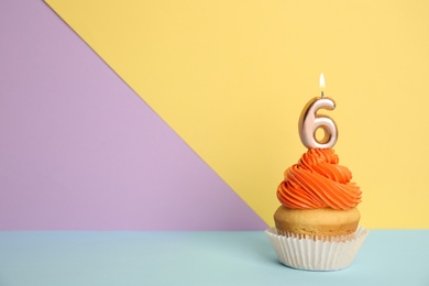 Photo of Birthday cupcake with number six candle on color background, space for text