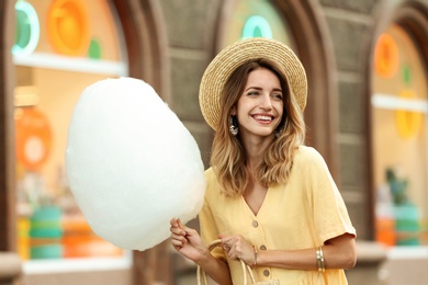 Photo of Happy young woman with cotton candy outdoors