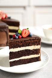 Photo of Plate with slice of chocolate sponge berry cake on grey table