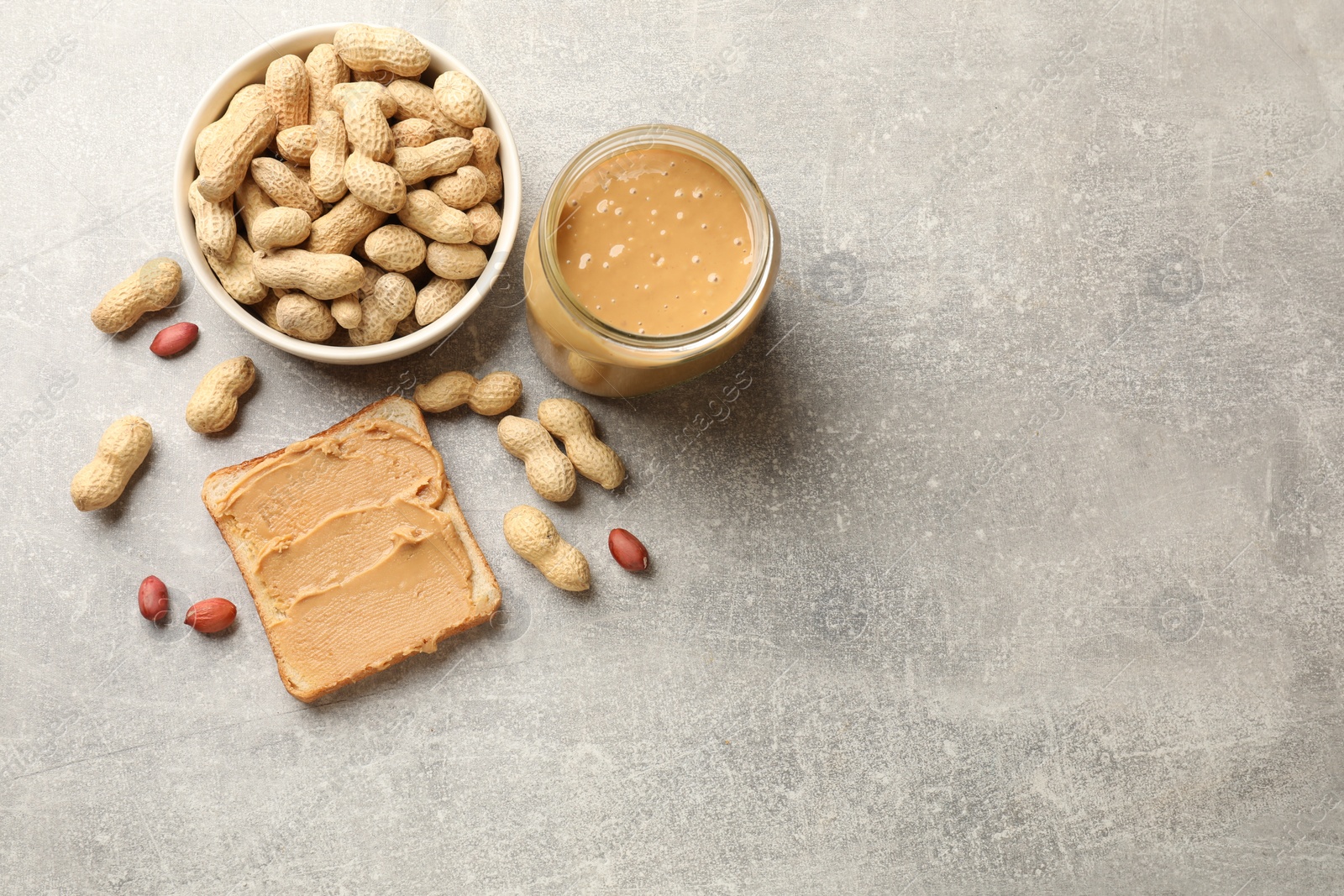 Photo of Tasty peanut butter sandwich and peanuts on gray table, flat lay. Space for text