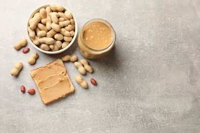 Photo of Tasty peanut butter sandwich and peanuts on gray table, flat lay. Space for text