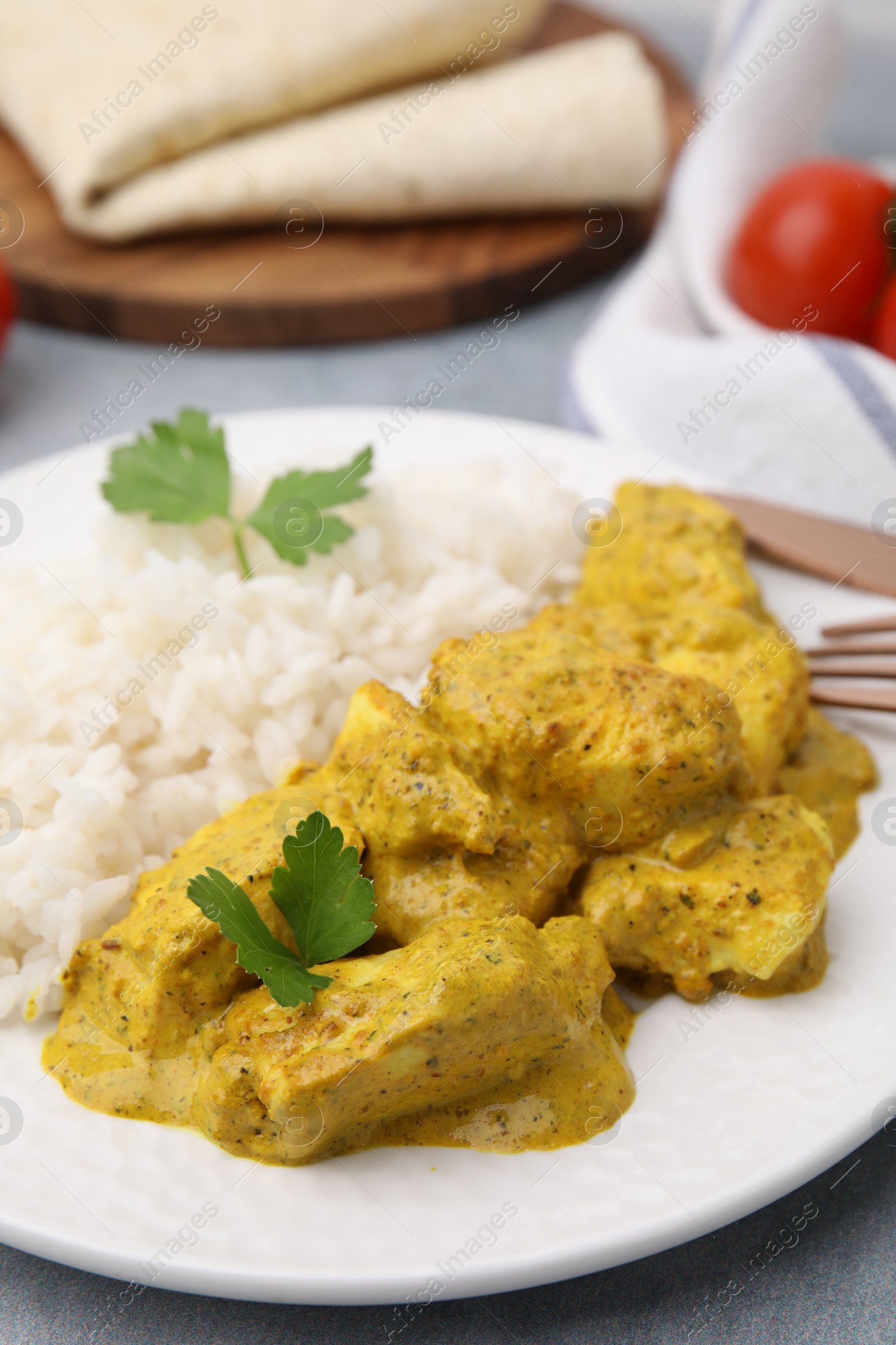 Photo of Delicious rice and chicken with curry sauce on light grey table, closeup