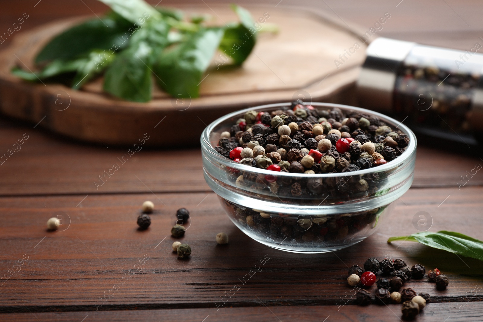 Photo of Glass bowl of mixed pepper corns on wooden table, space for text