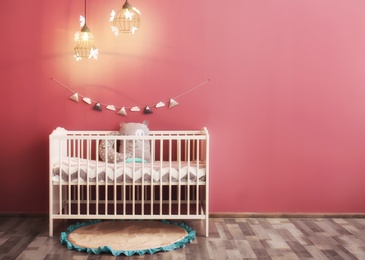 Modern baby room interior with crib near color wall