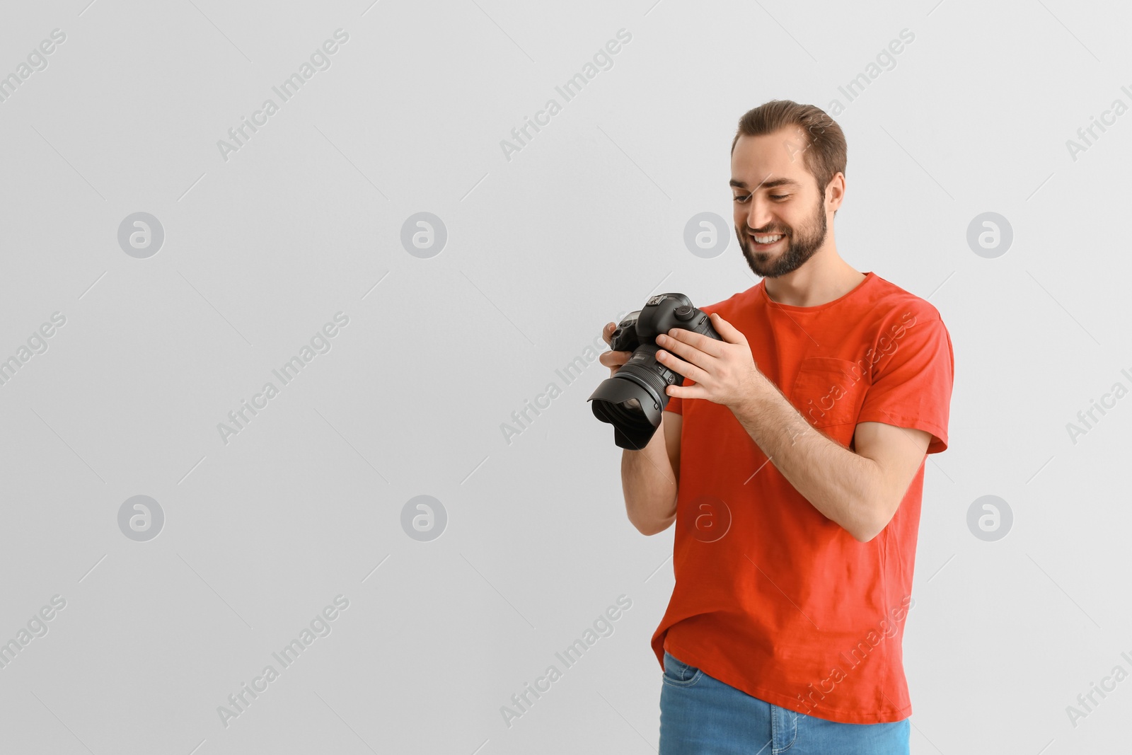 Photo of Young photographer with professional camera on white background