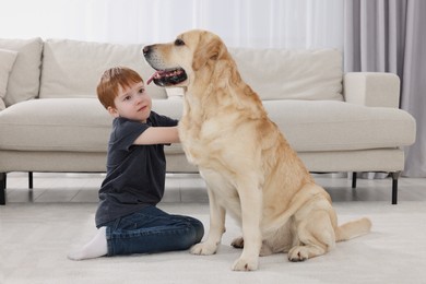 Photo of Cute child with his Labrador Retriever on floor at home. Adorable pet
