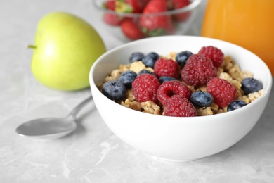 Photo of Healthy breakfast with granola and berries on light grey marble table, closeup