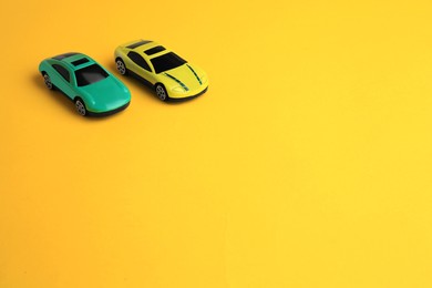 Photo of Bright cars on yellow background, space for text. Children`s toys