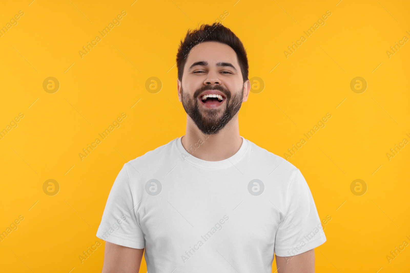 Photo of Handsome young man laughing on yellow background