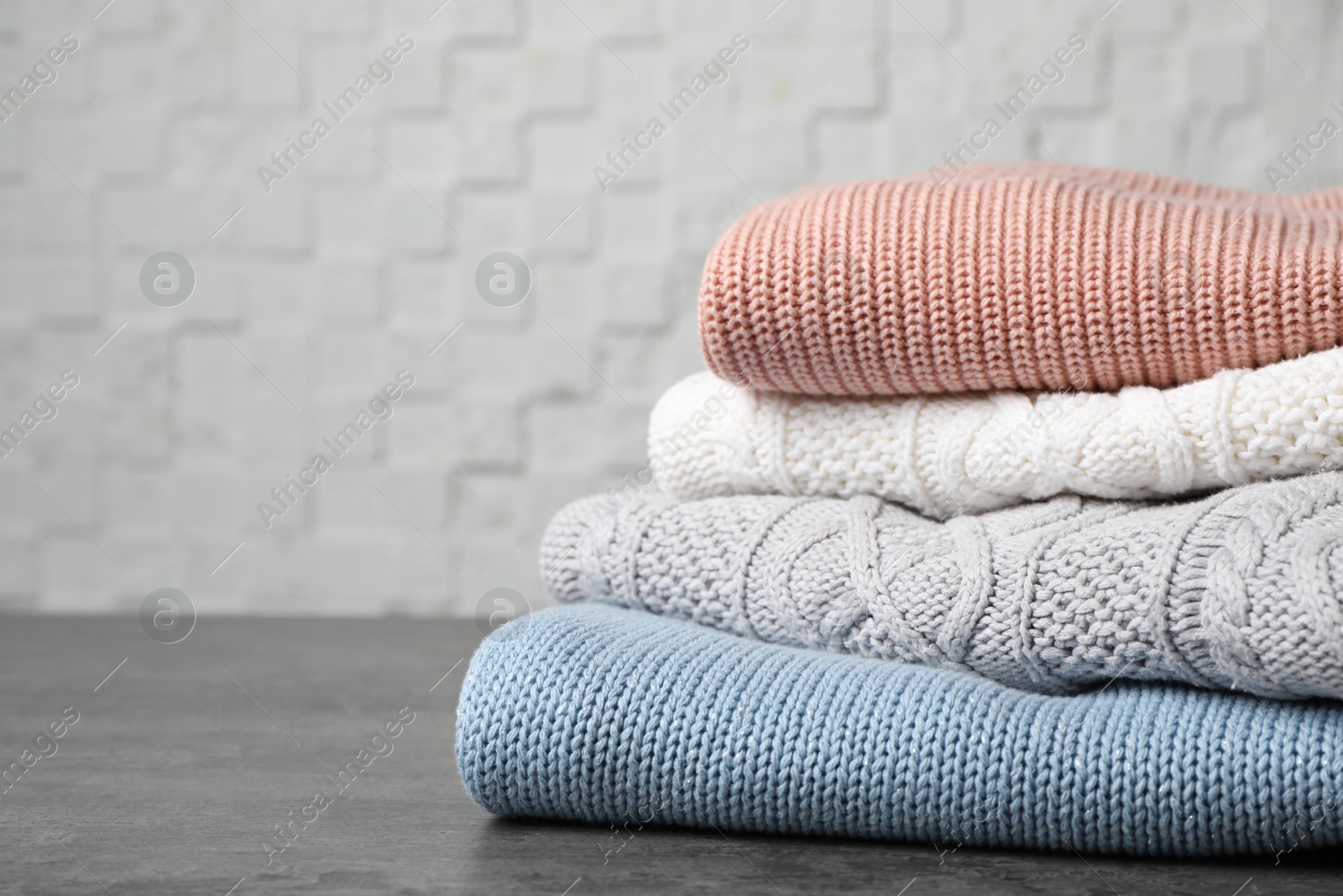 Photo of Stack of folded knitted sweaters on table. Space for text