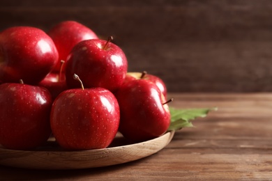 Photo of Plate with fresh ripe red apples on wooden table